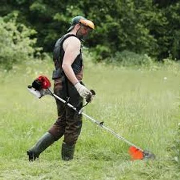 Man using a brush cutter in a grassy field.