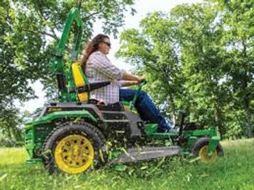 Person mowing lawn on a green riding mower.