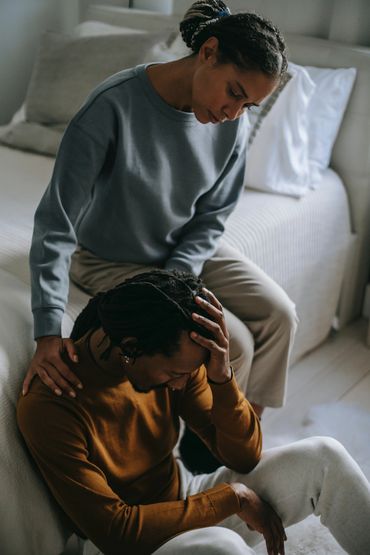 Partner supporting a sorrowful man at home