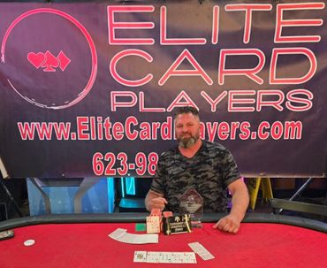 Man sitting at poker table with tournament winner plaque and chips.