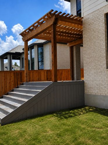 Wooden pergola with stairs leading to a house patio.