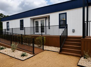 Modern white and blue building with wooden ramp and stairs.