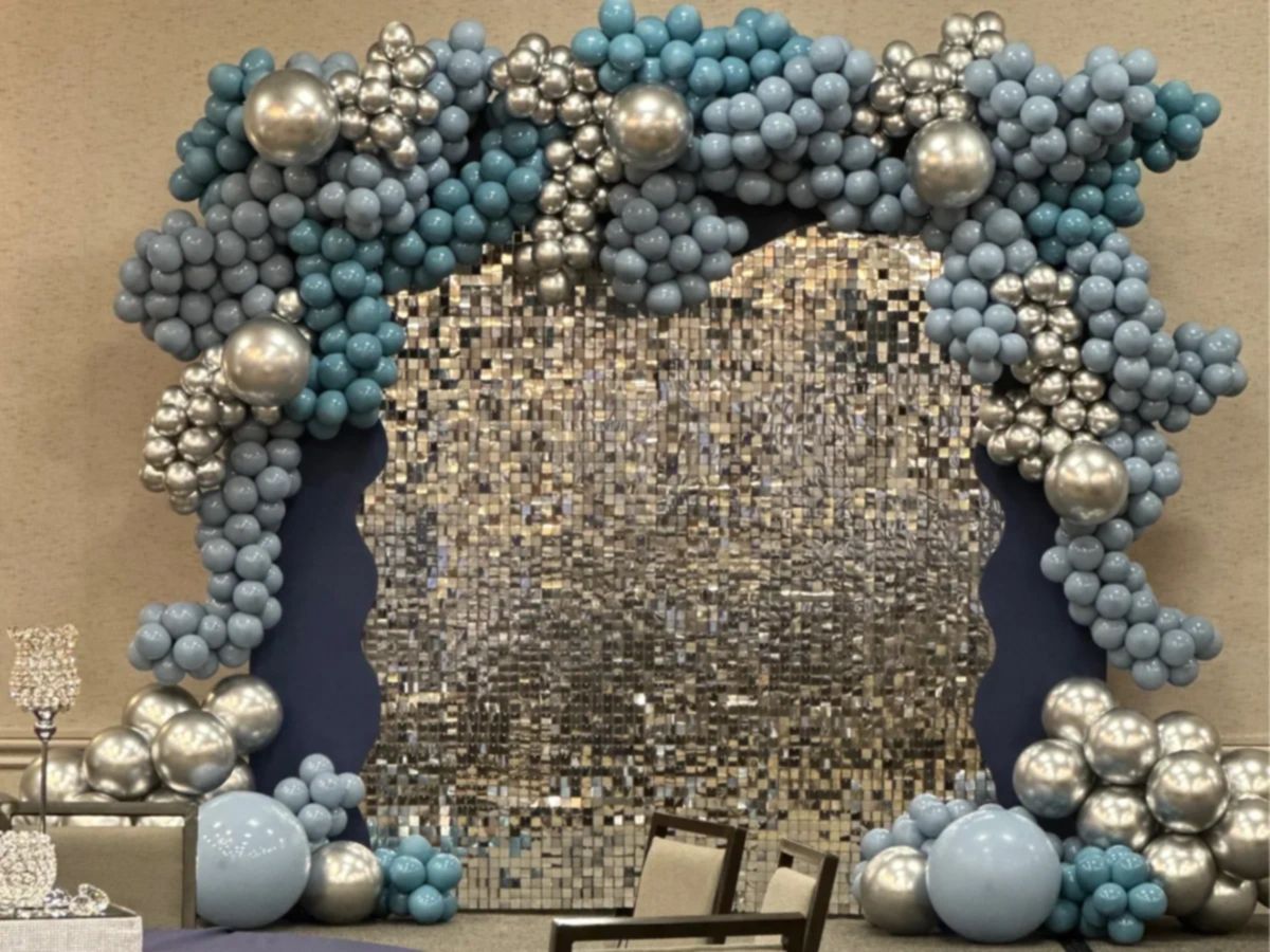 Elegant blue and silver balloon arch framing a shimmering mosaic backdrop.