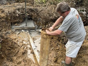 Plumber sliding a sleeve over a newly installed valve in order to direct water from a reservoir.