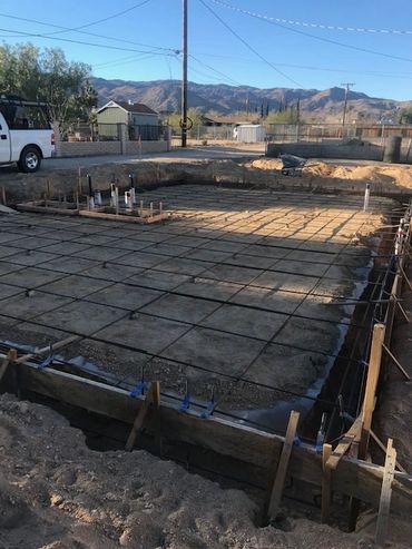 Construction site with rebar grid for concrete foundation.