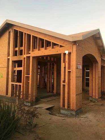 Wooden framework of a house under construction at sunset.