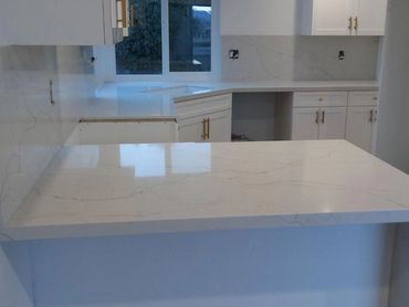 Modern kitchen with white marble countertops and cabinetry.