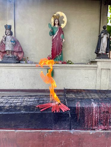 Lit red candles burning in front of religious statues and offerings.