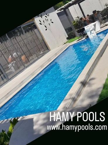 Modern rectangular swimming pool with clear blue water and patio seating.