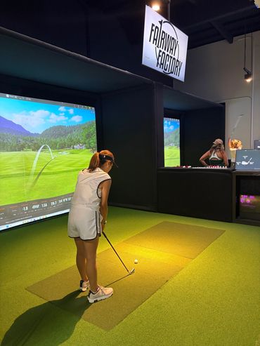 Woman playing golf at indoor simulator.