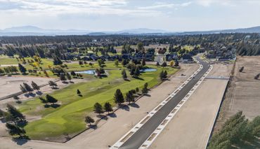 Aerial view of a golf course beside a newly paved road and residential area.