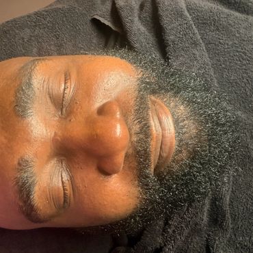 Close-up of a man with a beard resting on a black towel.