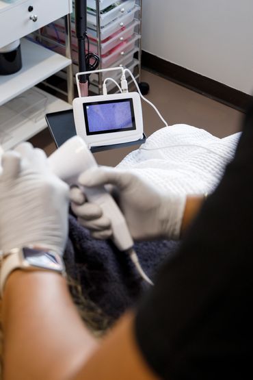 Medical professional using a handheld device connected to a monitor during a procedure.