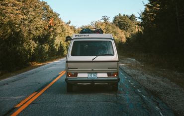 Rear view of a packed Westfalia camper van on a forest road.