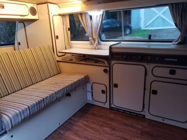 Cozy interior of a Westfalia camper van with striped seating and compact kitchen.