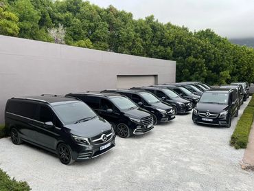 A row of black Mercedes V Class parked outside a Luxury villa.