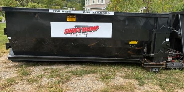Large black dumpster with rental contact information and company logo.