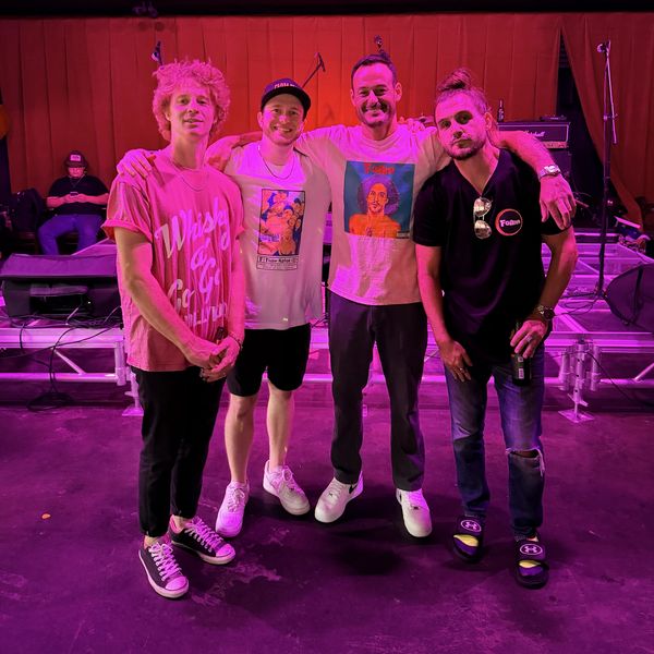 Four men posing together at an event with purple lighting.