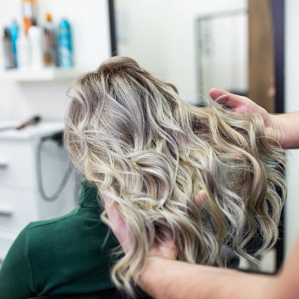 Curly Hair salon and hairstylist holding female clients' curly hair doing a Consultation