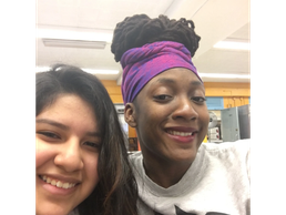 Two friends smiling in a bright indoor setting.