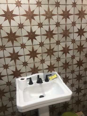 White sink with black faucets against star-patterned tile wall.