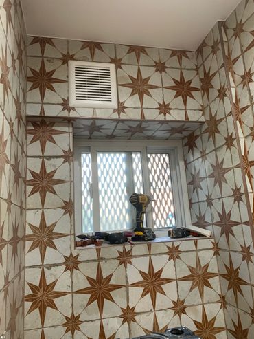 Window with tools on the sill and star-patterned tiles on walls.