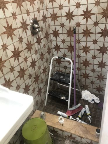 Bathroom under renovation with tools and cleaning supplies scattered.