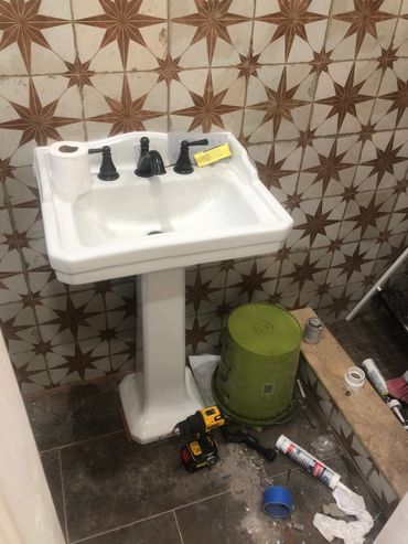 Bathroom sink area with tools and construction materials scattered around.