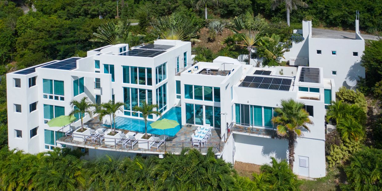 Modern white villa with solar panels and pool.