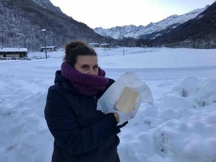 Giulia circondata dalla neve con un panetto di burro di panna cruda di affioramento in alta montagna