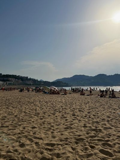 Strand mit vielen Menschen bei Sonnenuntergang.