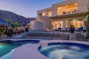 Modern desert home with pool and jacuzzi at dusk.