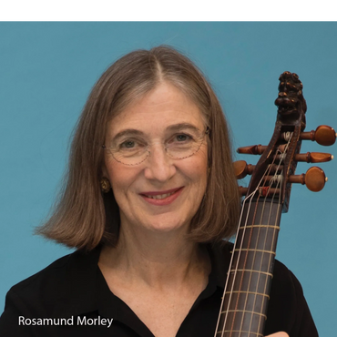 A smiling woman with glasses holding a string instrument against a blue background.