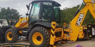 A yellow JCB backhoe loader on a flatbed truck.