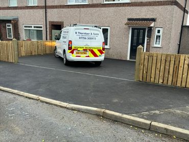 A white van parked on a newly paved driveway in front of a house.