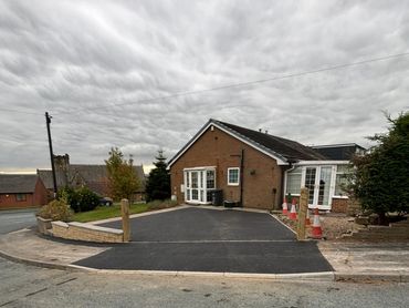 Newly paved driveway in front of a brick house under a cloudy sky.