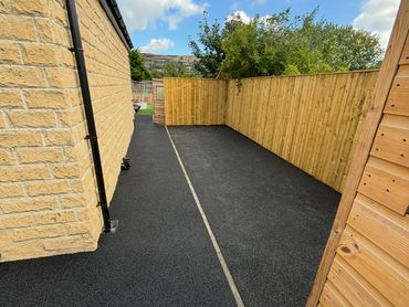Neat outdoor space with black rubberized flooring and wooden fence.