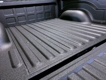 Close-up of a textured black truck bed liner with ribbed surface.