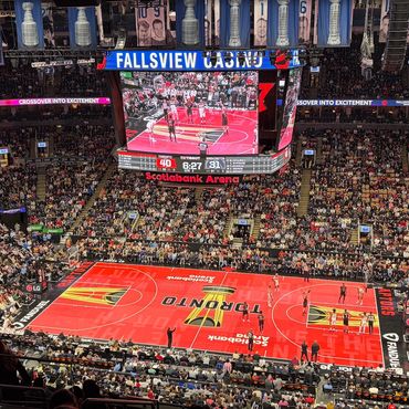 A packed basketball arena during a game with Toronto Raptors playing.