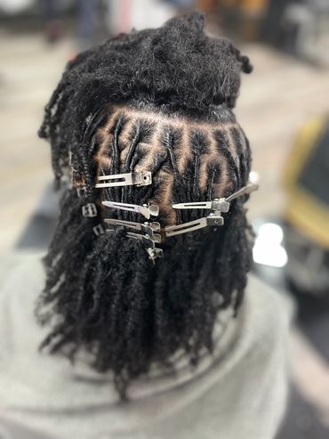 Intricate dreadlock hairstyle sectioned and secured with multiple hair clips.
