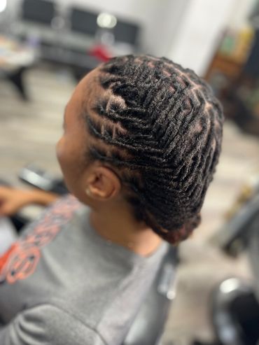 Intricate twisted dreadlock hairstyle on a person's head.