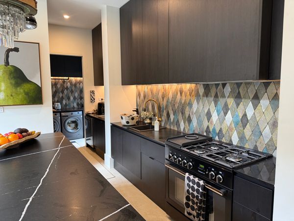 Modern kitchen with dark cabinetry and patterned backsplash.