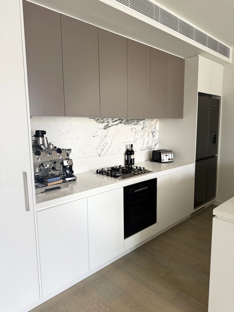 Modern kitchen with sleek appliances and marble backsplash.
