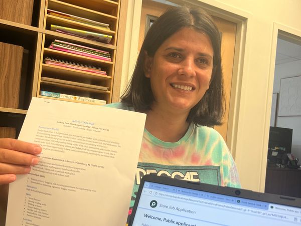 Woman holding a resume and laptop with job application.