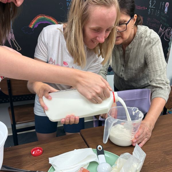 People pouring milk into a measuring cup.