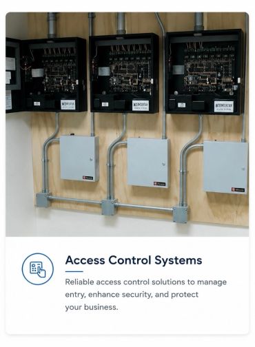 Three open access control panels mounted on a wooden wall with metal conduit wiring.