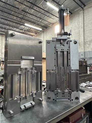 Two large metal molds or dies on a workbench in an industrial workshop.