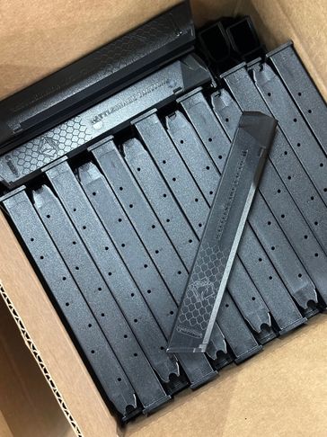 A box filled with multiple black firearm magazines.