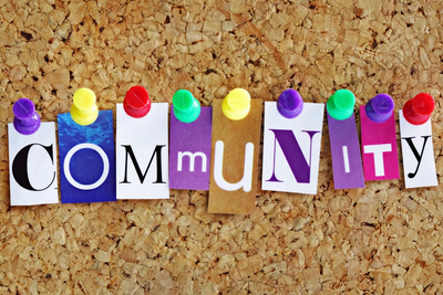 The word COMMUNITY is spelled out with colorful letters pinned on a corkboard.