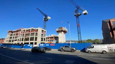 Construction site with cranes and partially built structures under a clear blue sky.
